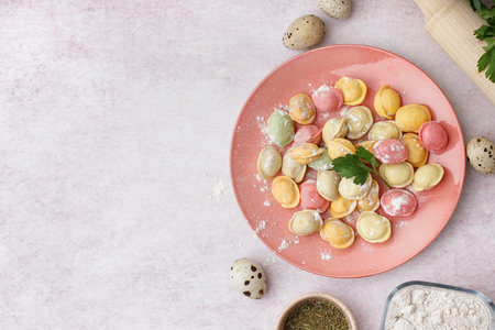Plate with colorful raw dumplings and parsley on white background