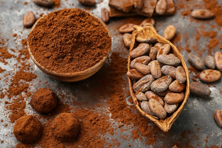 Bowl with cocoa powder, candies and beans on black backgroundの写真素材
