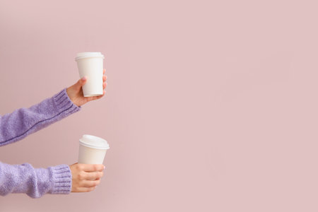 Female hands with takeaway paper cups on purple backgroundの写真素材
