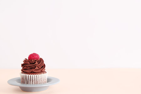Plate of tasty chocolate cupcake with raspberry on beige backgroundの写真素材
