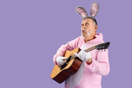 Senior man in Easter bunny costume playing guitar on lilac background