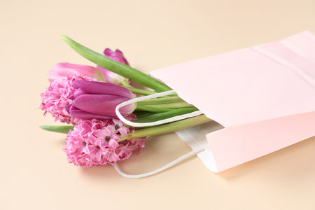Paper shopping bag with pink flowers on beige backgroundの写真素材