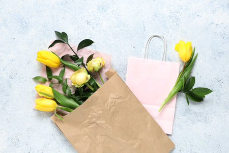 Paper shopping bags with flowers and green twigs on blue grunge backgroundの写真素材