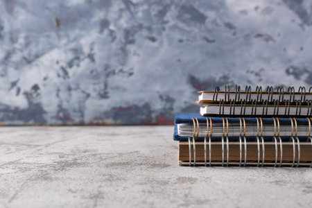 Stack of notebooks on grunge table near gray wall