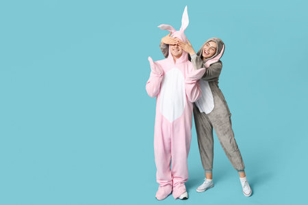 Beautiful young couple in bunny costume on blue background. Easter celebration