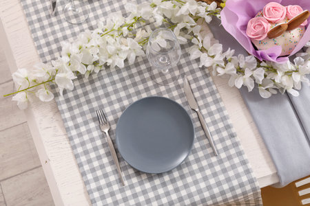 Stylish festive table setting with flowers, Easter cakes and painted eggs