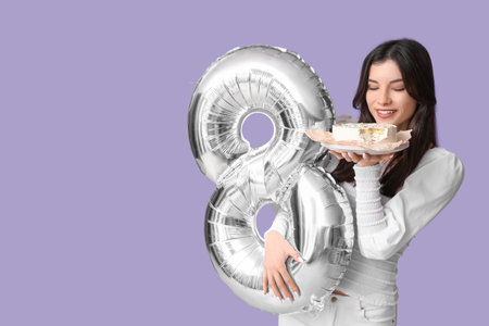 Beautiful young woman with sweet bento cake and air balloon in shape of figure 8 on lilac background. International Women's Dayの写真素材