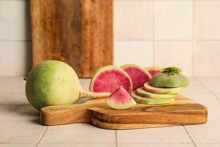 Wooden board with cut ripe watermelon radish on white tile backgroundの写真素材