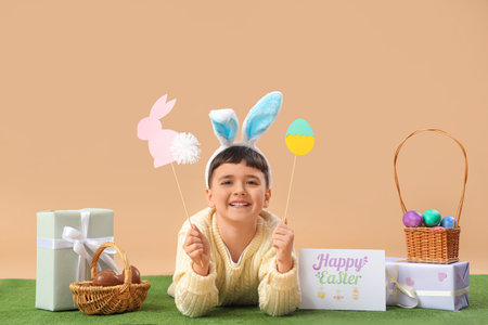 Cute little boy in bunny ears headband with baskets of eggs, gift boxes and festive postcard for...