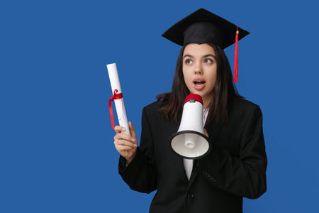 Female student in graduation hat with diploma and megaphone on blue background