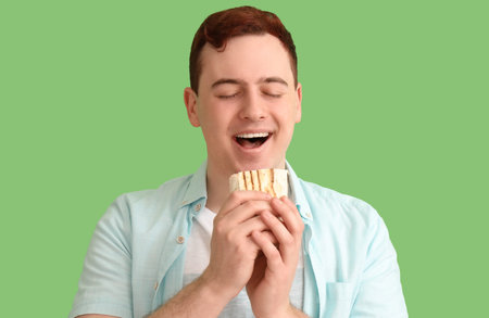 Young happy man eating doner kebab on green background