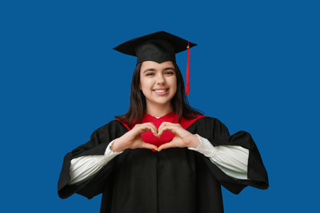 Happy female advancing student making heart with her hands on blue backgroundの写真素材