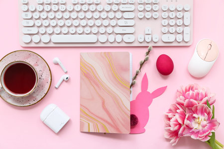 Composition with notebook, gadgets, cup of tea and Easter decor on pink background