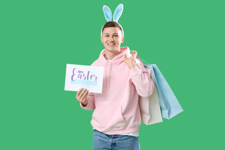 Young man in bunny ears holding paper with text EASTER SPECIAL SALE and shopping bags on green...