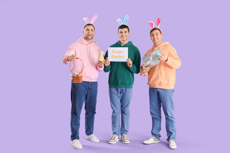 Happy young men in bunny ears celebrating Easter on purple background