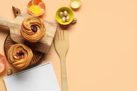 Blank notepad for recipes with sweet buns, Easter eggs and baking tools on beige background