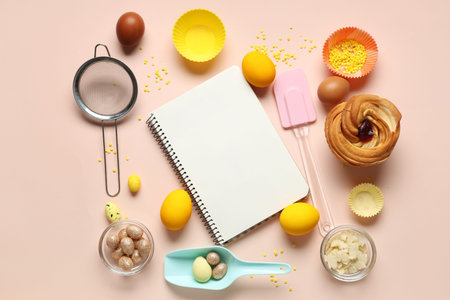 Blank notepad for recipes with sweet bun, Easter eggs and kitchen tools on beige background