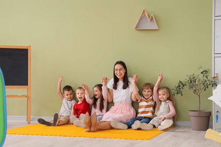Little children with nursery teacher holding hands in kindergartenの写真素材