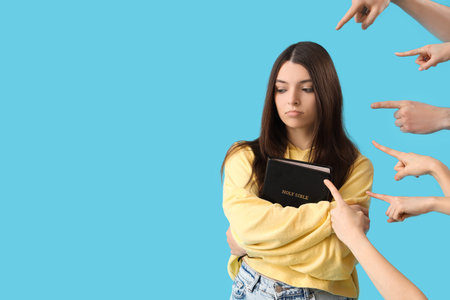 People pointing at young woman with Holy Bible on blue background. Accusation concept