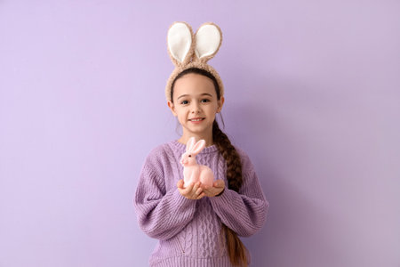 Cute little girl with bunny ears and toy rabbit on lilac background. Easter celebration