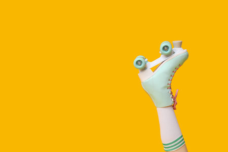Leg of beautiful young woman in vintage roller skates on yellow backgroundの写真素材