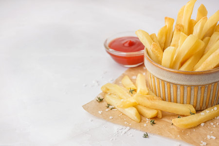 Bowl of tasty French fries on white background