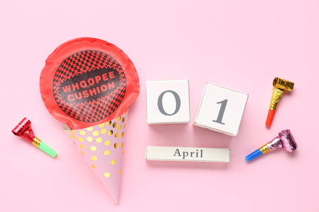 Calendar with whoopee cushion, party hat and whistles on pink background. April Fools Day celebrationの写真素材