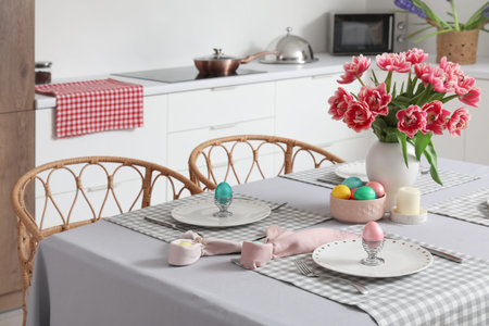 Dining table set for Easter with eggs and tulips in kitchen