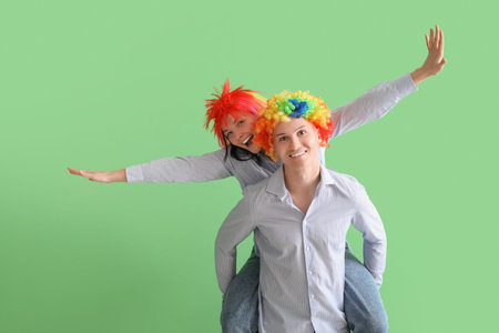 Business colleagues in funny wigs on green background. April Fools' Day celebrationの写真素材
