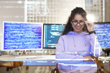 Female African-American programmer with projection of code in office at nightの写真素材