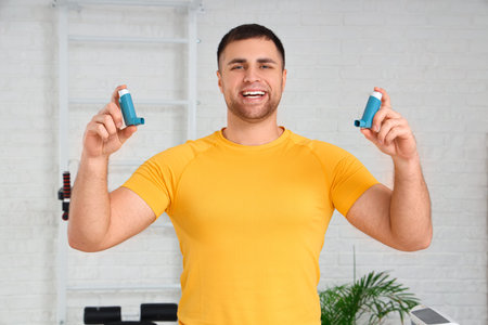 Sporty young man with inhalers in gym