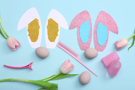 Hairdressing accessories with Easter eggs, paper bunny ears and tulips on blue backgroundの写真素材