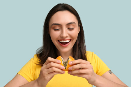 Beautiful young woman with tasty passion fruit on blue background