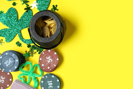 Poker chips, pot with coins and clovers on yellow background. St. Patrick's Day celebrationの写真素材