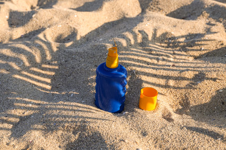 Bottle of sunscreen cream on sand at sea beach
