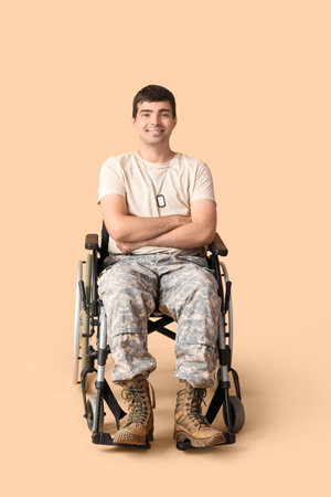 Young soldier in wheelchair on beige backgroundの写真素材