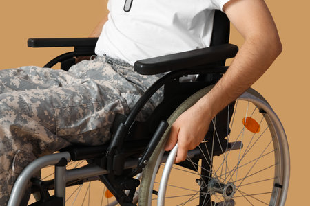 Young soldier in wheelchair on beige background, closeupの写真素材