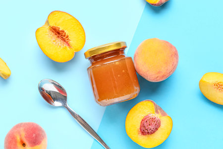 Composition with glass jar of sweet peach jam and fresh fruits on color background