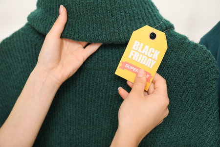 Female hands with sale tag and sweater, closeup. Black Friday