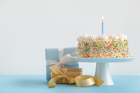 Stand with yummy Birthday cake and gift boxes on color background