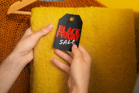 Female hands with sale tag and warm scarf, closeup. Black Fridayの写真素材