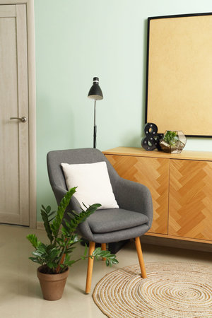 Interior of living room with armchair, drawers and lamp