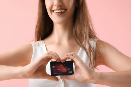 Young woman with credit card on pink background, closeup