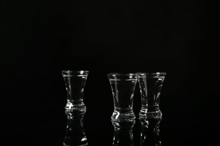 Shots of cold vodka on black background