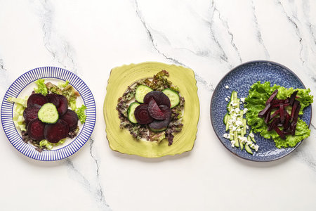 Plates with tasty vegetable salads on light background