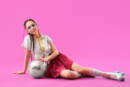 Young woman with dreadlocks and roller skates on pink background