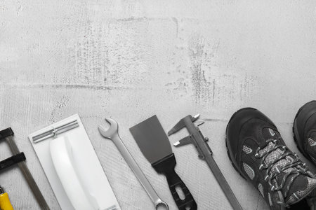 Set of construction tools and shoes on gray background