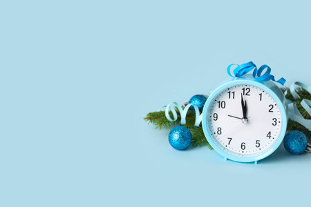 Alarm clock and Christmas tree branches with balls on blue background