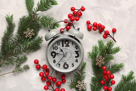 Alarm clock and Christmas tree branches with rowan on gray background