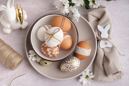 Plates with decorated Easter eggs, bunny and spring flowers on white background